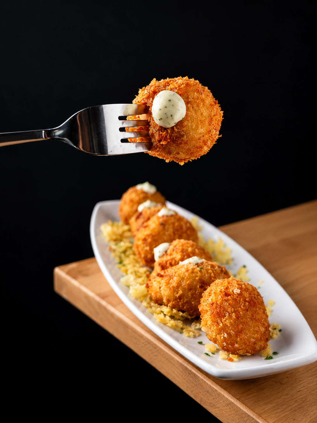 Croquetas doradas presentadas en un plato sobre mesa de madera